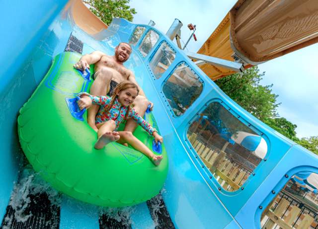 Father and daughter on waterslide together.