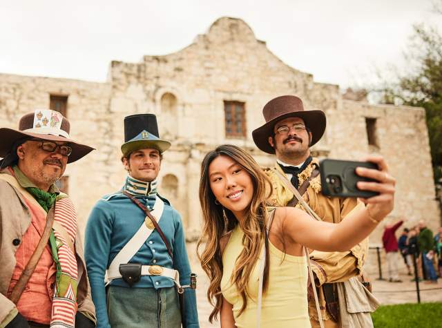 Girl taking a selfie with Alamo staff in costume