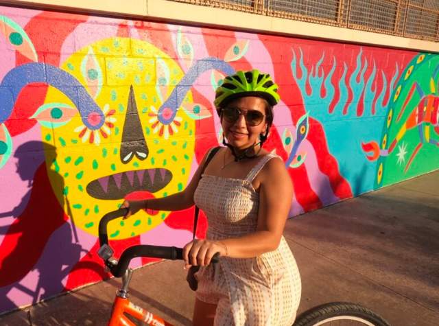 Girl with bike helmet on bike in front of mural