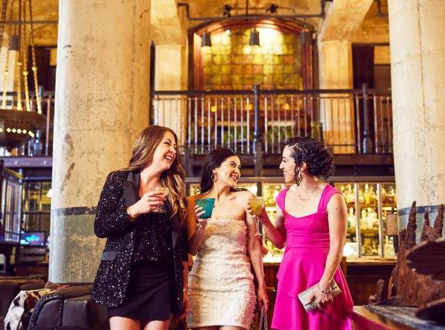 Three girls enjoying drinks in beautiful room with two large pillars