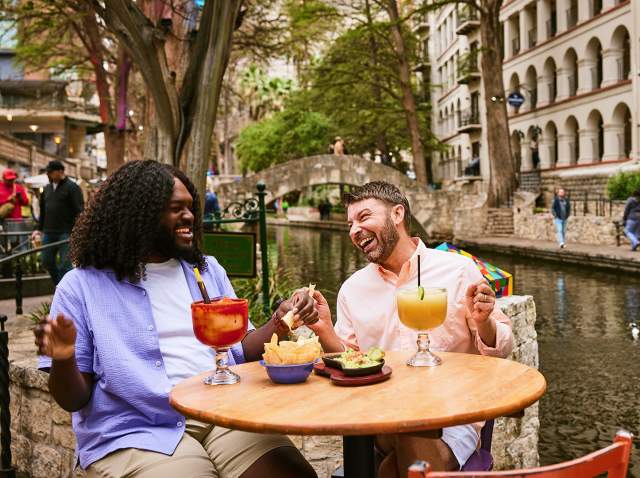Two men on the River Walk enjoying chips and margaritas