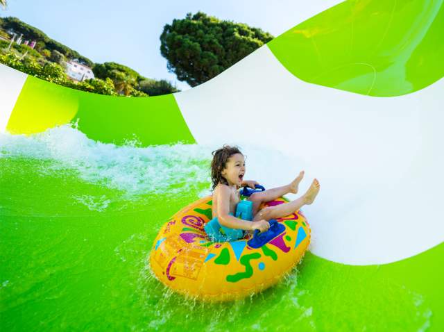 Child on inner tube on waterslide laughing.
