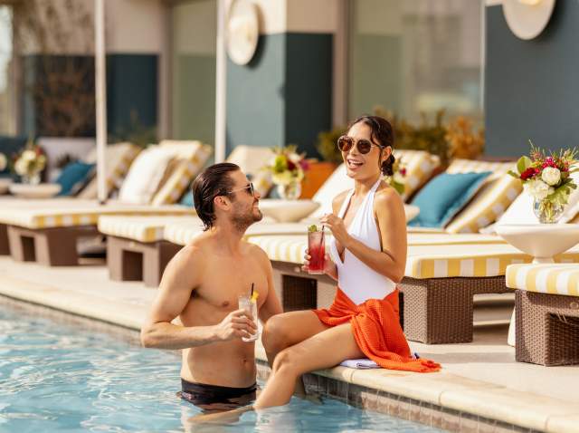 Man and woman drinking cocktails poolside at Hotel Contessa.