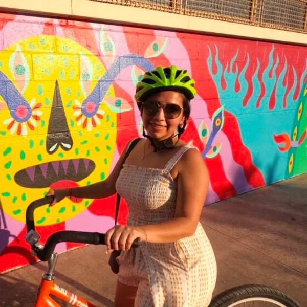 Girl with bike helmet on bike in front of mural