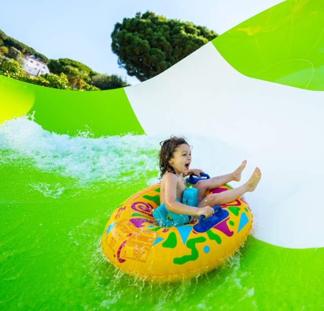 Child on inner tube on waterslide laughing.