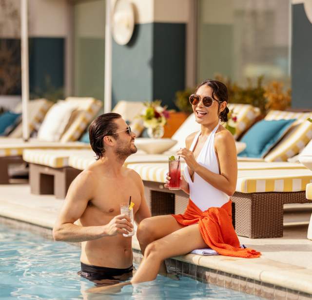 Man and woman drinking cocktails poolside at Hotel Contessa.