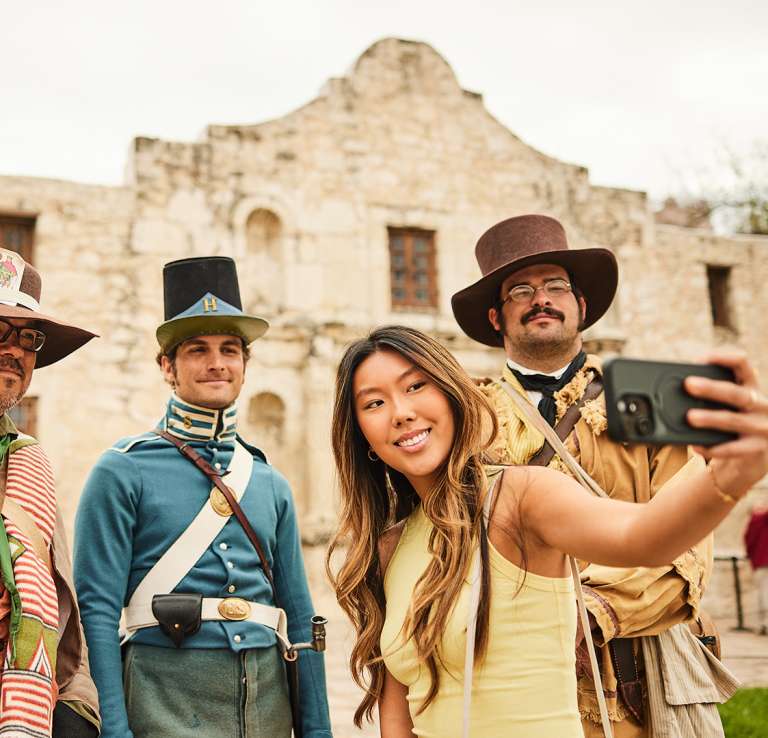 Girl taking a selfie with Alamo staff in costume
