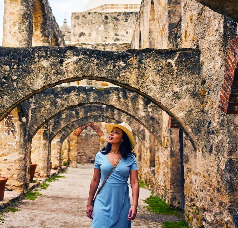 Woman walking under arches at missions