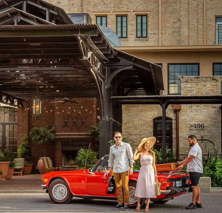 Man and woman exiting sports car at Hotel Emma.