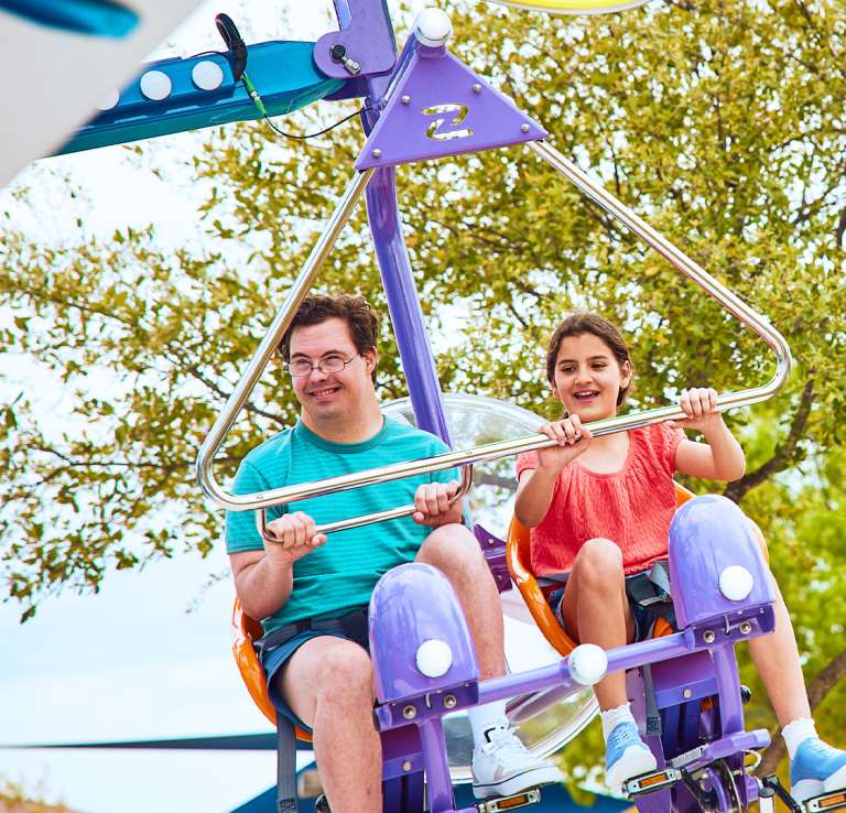 Boy and girl on air ride with trees behind them