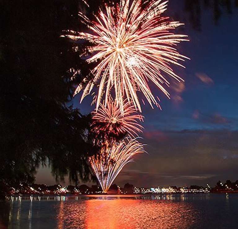 Fireworks going off over water at Woodlawn Lake Park.
