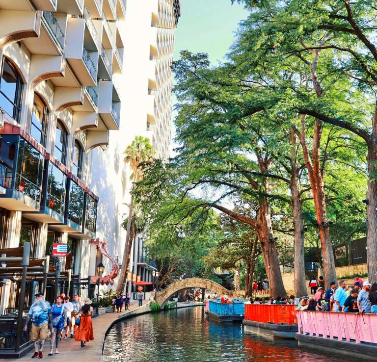 River barges on San Antonio River Walk floating by hotels.