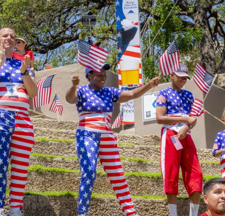 Family dressed in patriotic attire handing out flags.