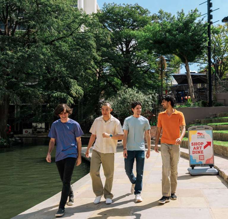 Group of men walking along River Walk in San Antonio.