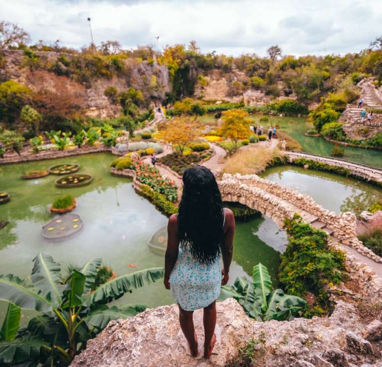 Woman overlooking lush garden and standing water at Japanese Tea Garden.