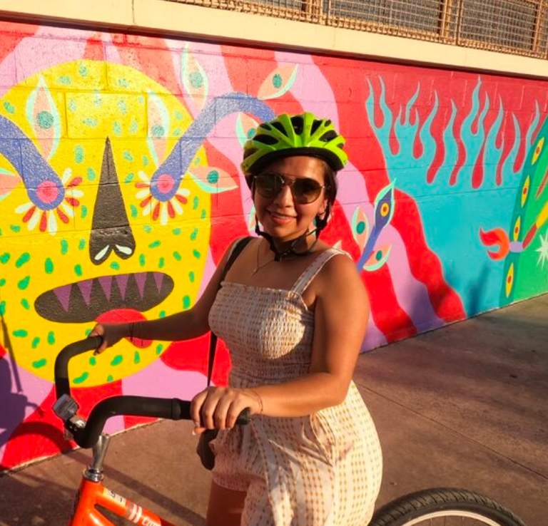 Girl with bike helmet on bike in front of mural