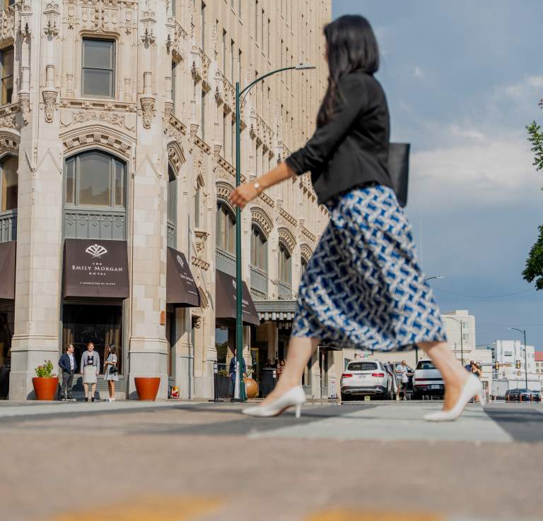 Woman in professional clothing walking in front of the Emily Morgan Hotel.