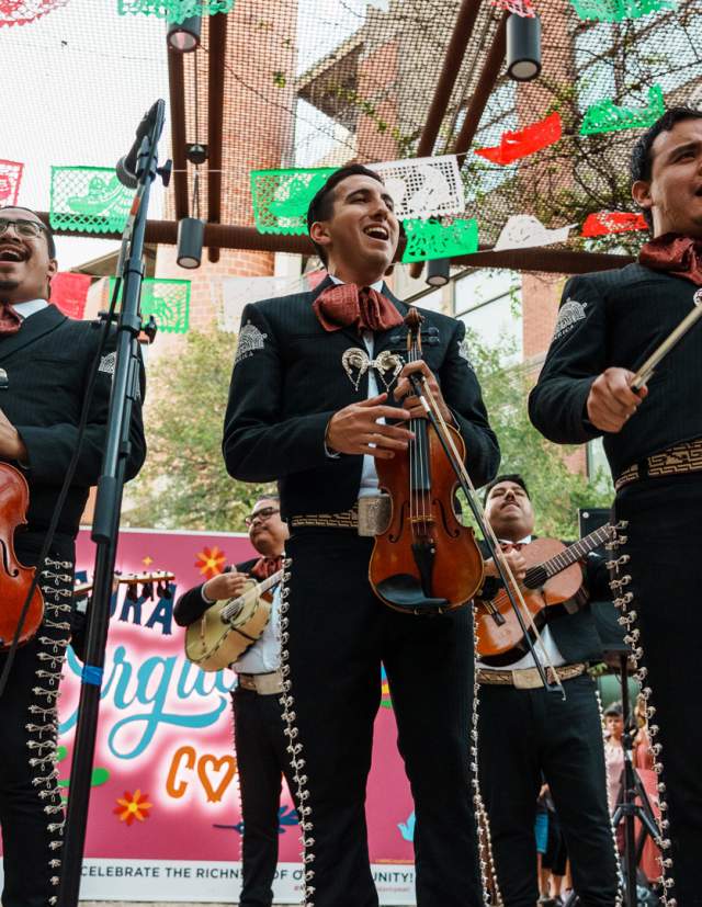 Mariachis standing in front of papel picado
