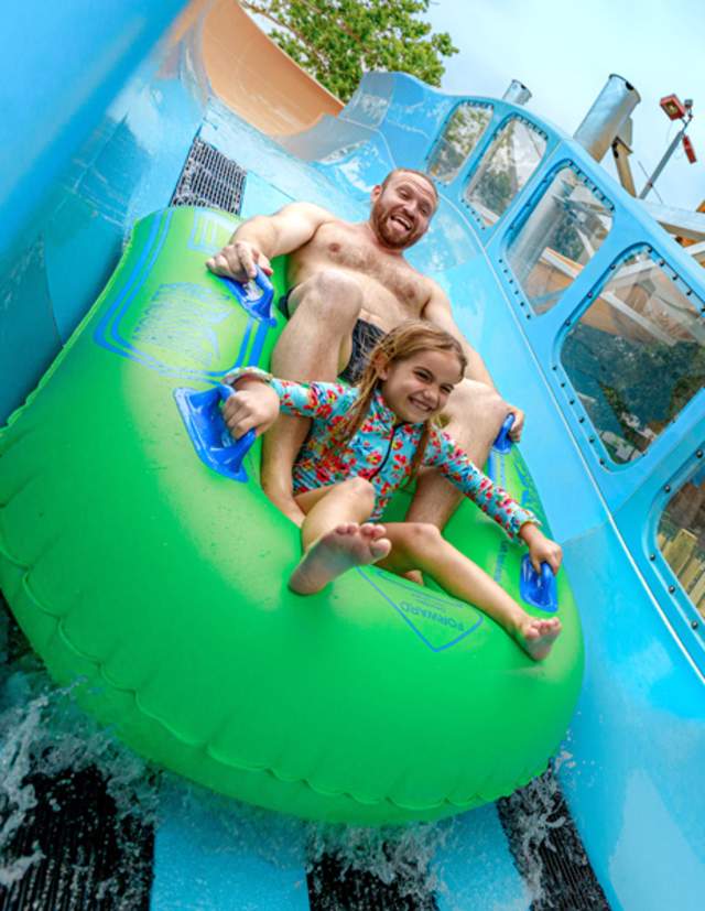 Father and daughter on waterslide together.