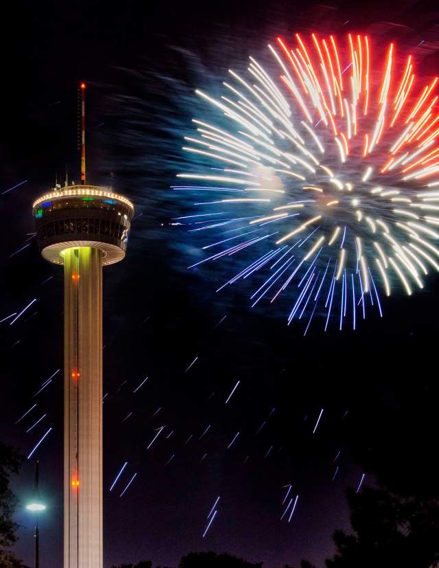 Red, white, and blue fireworks in front of crowd at Tower of the Americas.