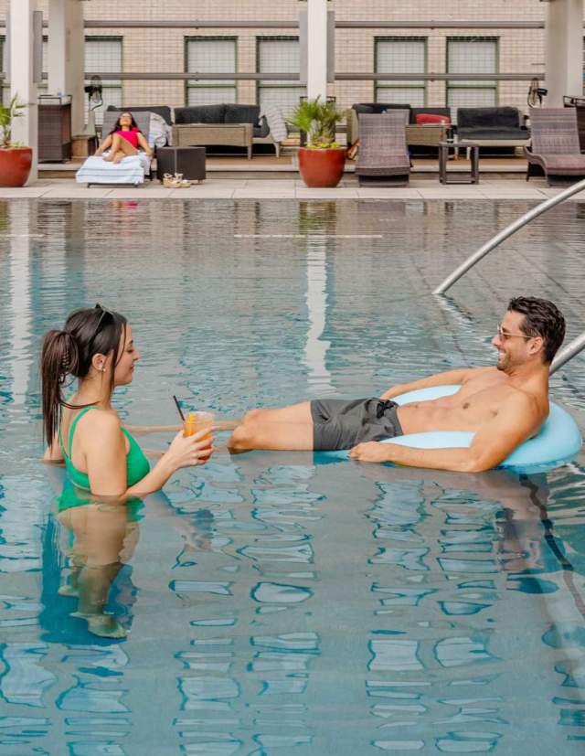 Man and woman enjoying a drink and the pool at St. Anthony Hotel in San Antonio.
