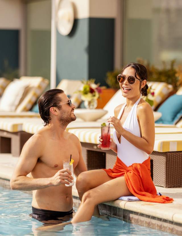 Man and woman drinking cocktails poolside at Hotel Contessa.