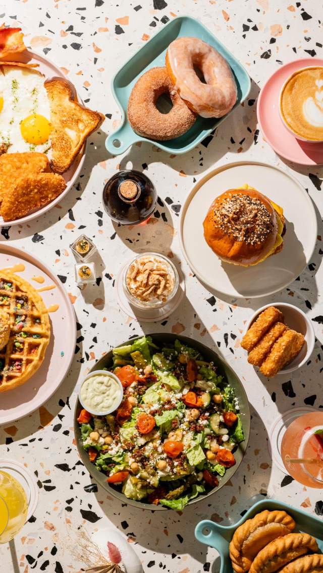 Overhead view of breakfast spread with waffles and donuts.