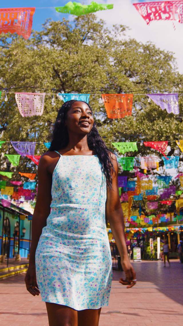 Woman walking through Historic Market Square with. papel picado in background.