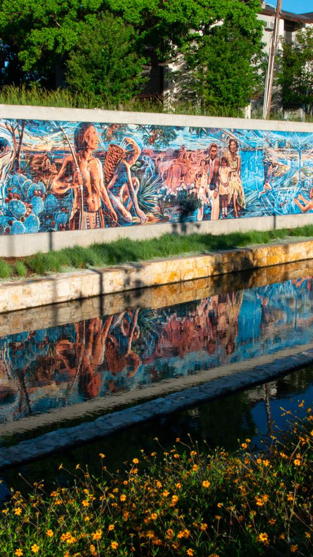 Public art along wall in front of creek
