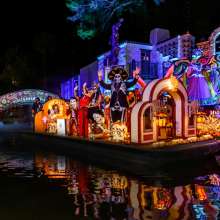 Nighttime river parade with parade float decorated with Dia de los Muertos decor
