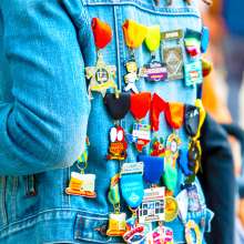 Back of person wearing jean jacket filled with Fiesta medals.