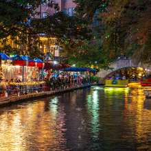 Calm river along River Walk with holiday lights and patio dining in background