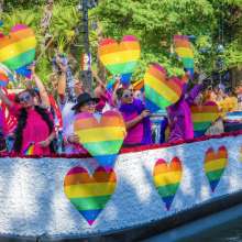 River barge with rainbow hearts and people floating on River Walk