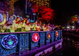 Mariachi band members on a river barge drifting in the Day of the Dead River Parade.