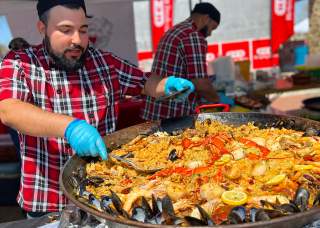 Man scooping paella onto plate.