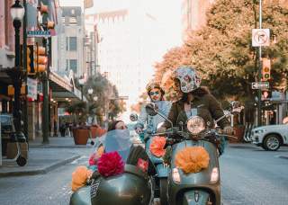 Woman driving vespa with passenger in side car in San Antonio, Texas.