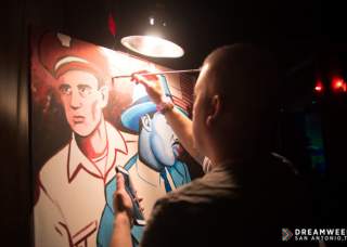 man painting in the dark with an overhead lamp
