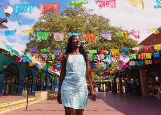 Woman walking through Historic Market Square with. papel picado in background.