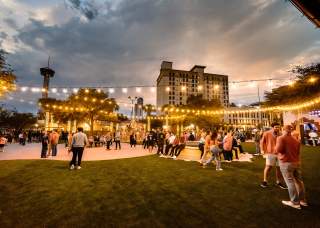 Large outdoor gathering at dusk with decorative lighting