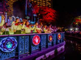 Mariachi band members on a river barge drifting in the Day of the Dead River Parade.