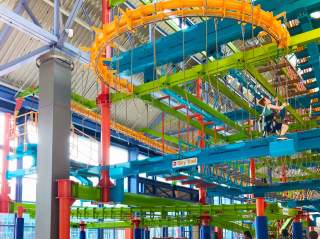 Ground-level view of LiggettVille Adventure Center multi-colored high-rise obstacle course.