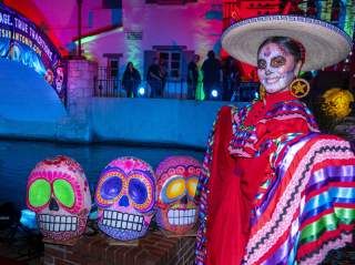 Woman dressed in a pancho with a sugar skull face painting.