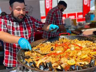 Man scooping paella onto plate.