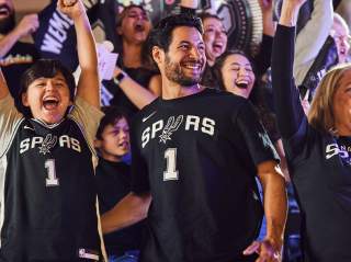 Fans cheering at game wearing Spurs shirts and jerseys
