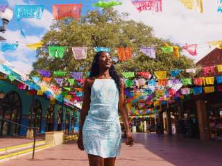 Woman walking through Historic Market Square with. papel picado in background.