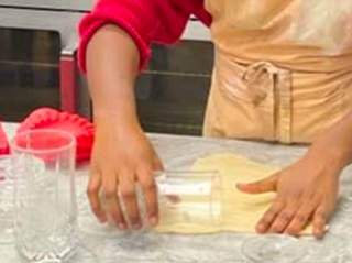 Dough being rolled using a drinking glass