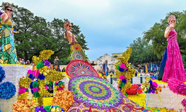 Parade participants on float dressed in elaborate dresses at Battle of Flowers parade in San Antonio in Fiesta San Antonio.