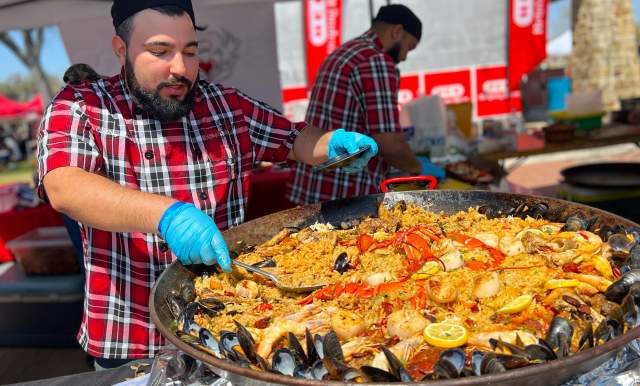 Man scooping paella onto plate.