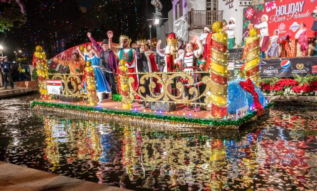 Festive decorated float with costumed patrons at Ford Holiday River Parade.