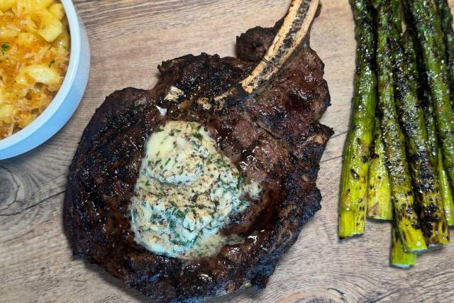 steak, asparagus and mac and cheese on wooden board